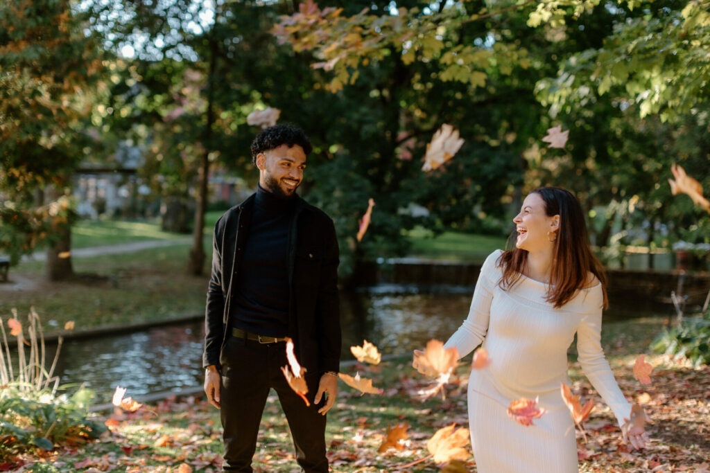 Future maman qui rit sous une pluie de feuilles